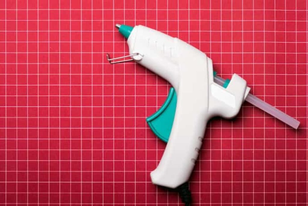 Pistola de cola quente em fundo vermelho